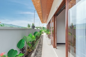 A modern building with a covered walkway lined with potted plants and a view of the landscape. - Genta Villa, Lovina - Villa Dua (Buleleng)