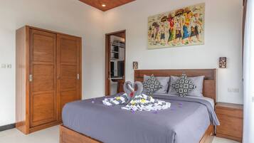 Une chambre avec un grand lit, une armoire en bois, un tableau au mur et une table de chevet avec une lampe.