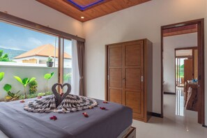 A bedroom with a bed, a wardrobe, and a view of the outdoors.