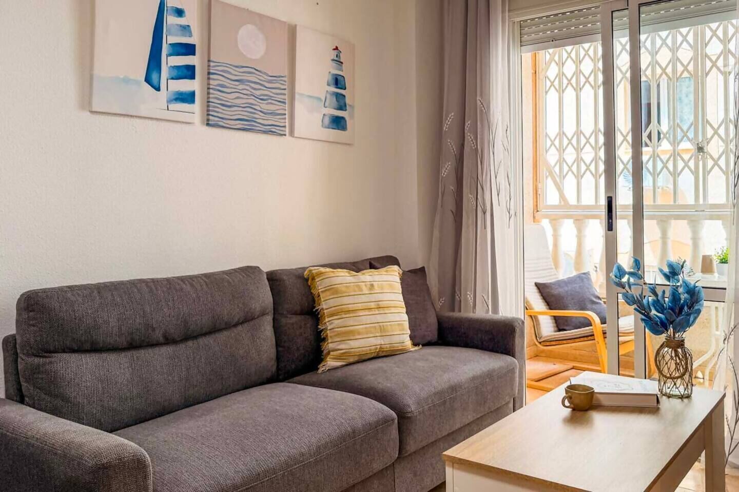 A living room with a grey sofa, a wooden coffee table, and a window with a view of buildings.