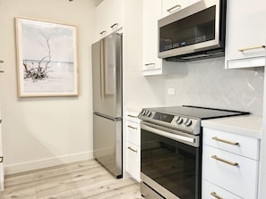 A kitchen with a stainless steel refrigerator, a built-in oven, and a microwave. - Chic Little Italy Condo - Pool, Valet Parking (San Diego)
