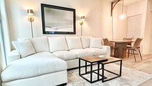 Ein modernes Wohnzimmer mit einem Ecksofa, einem Couchtisch und einem Essbereich mit Stühlen und einem Tisch.