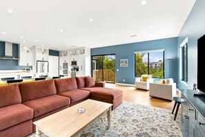 A modern living space with a kitchen, a sofa, a coffee table, and a view of the outdoors. - Sunny Palms Luxury Home - Northpark (San Diego)