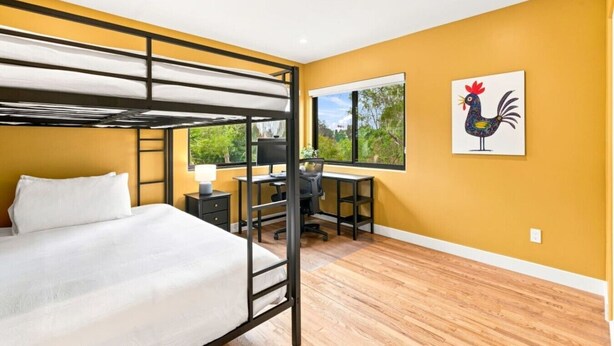 A room with a bunk bed, a desk with a computer, a chair, and a window with a view of greenery. - Sunny Palms Luxury Home - Northpark (San Diego)