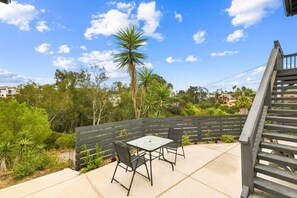 An outdoor patio with a table and chairs, surrounded by a wooden fence and greenery. - Sunny Palms Luxury Home - Northpark (San Diego)