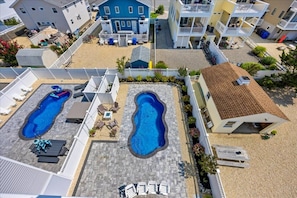 A residential area with two swimming pools, a covered patio, and a two-story building. - Coastal Luxury w/ Pool, Rooftop Deck, Elevator (Beach Haven)