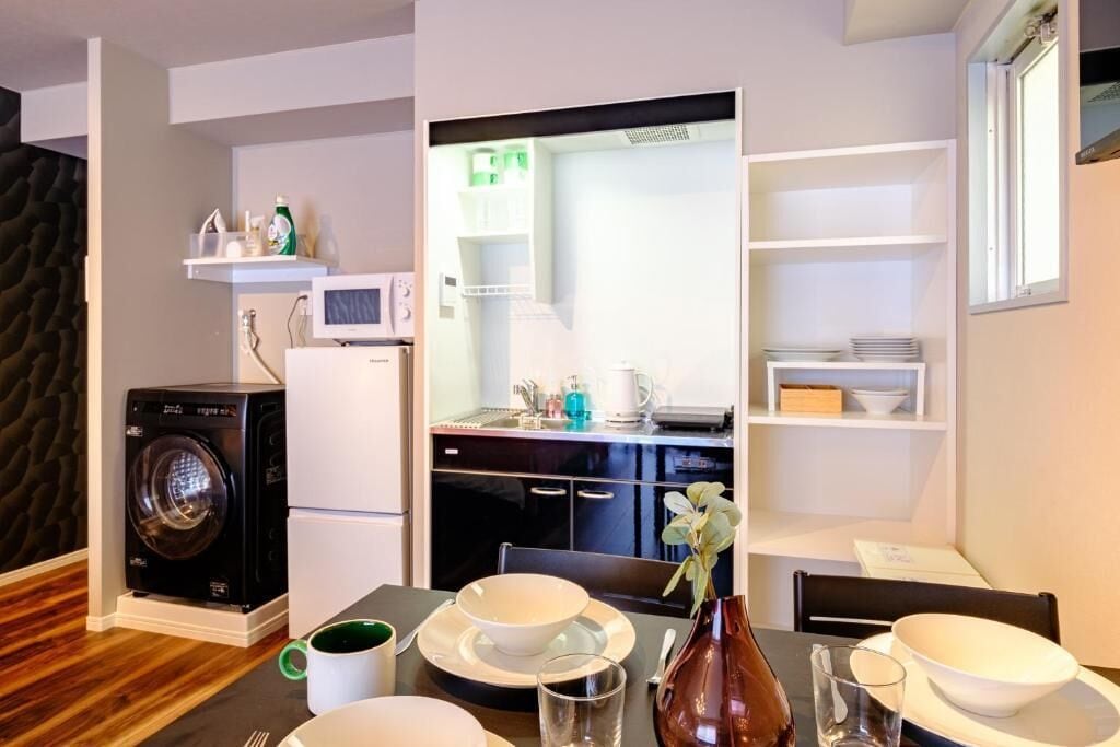 A compact kitchen with a washing machine, a microwave, and a dining area with a table set for two.