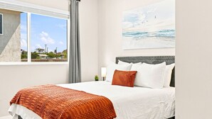 A bedroom with a bed, a window with a view of the outside, and a painting on the wall. - New 2BR Home Minutes to Downtown SD (San Diego)