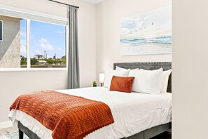 A bedroom with a bed, a window with a view of the outside, and a painting on the wall. - New 2BR Home Minutes to Downtown SD (San Diego)