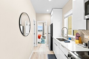 A modern kitchen with a built-in oven, a microwave, and a sink. There is a window with a view of the outside. - New 2BR Home Minutes to Downtown SD (San Diego)