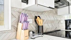 A modern kitchen with a herringbone tile backsplash, a knife block, a coffee maker, and a countertop. - New 2BR Home Minutes to Downtown SD (San Diego)