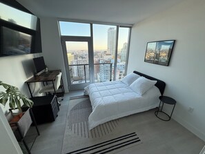Ein modernes Schlafzimmer mit großem Fenster, einem Bett, einem Schreibtisch und einem Stuhl.