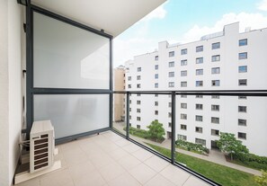 Ein Balkon mit Blick auf ein mehrstöckiges Gebäude, eine Heizung und einen klaren Himmel.