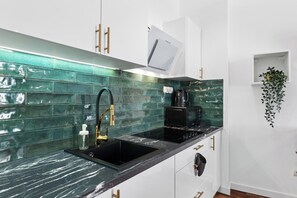 A modern kitchen with a black sink, stainless steel faucet, and a coffee machine. - Cyrulicza Old Town Apartment (Lublin)