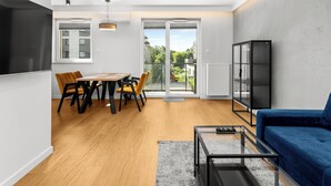 Ett modernt vardagsrum med en matplats, en soffa, ett soffbord i glas och utsikt över omgivningarna.