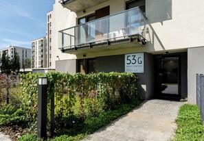 A modern building with a balcony, a sign indicating the address, and a well-maintained garden area. - Krowodrza Superior Apartment (Kraków)