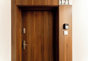 Eine Holztür mit einem Schild mit der Nummer 121 darüber, einem Schlüsselloch, einem Türgriff und einem digitalen Schloss auf der rechten Seite.