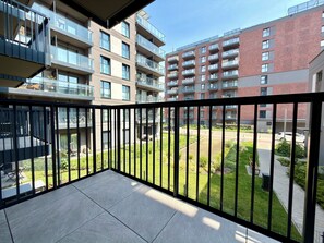 A balcony with a view of a residential building complex, featuring multiple balconies and a well-maintained lawn. - Madalińskiego Prime Studio 3B (Wrocław)