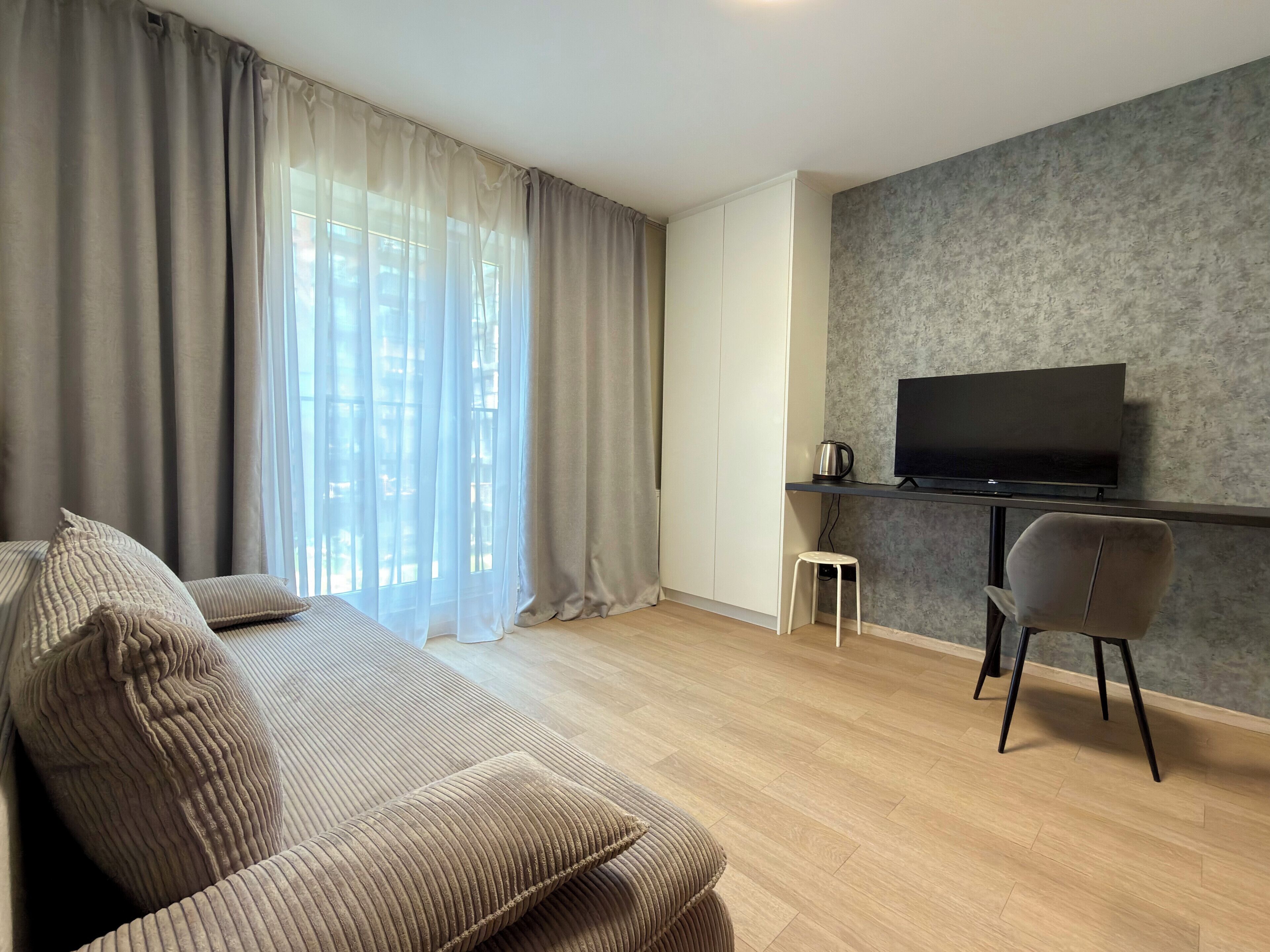 Una sala de estar moderna con un sofá, un televisor, una mesa de centro y un taburete pequeño.