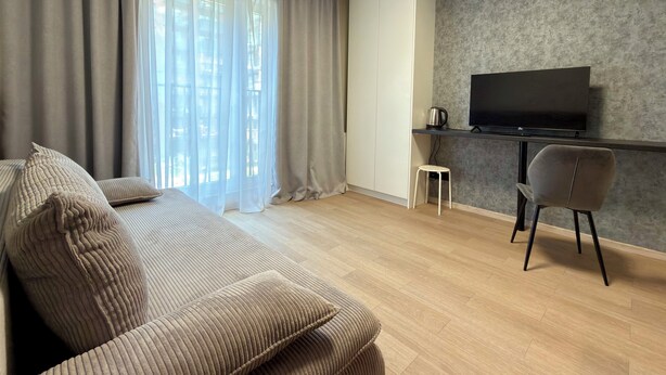 Ein modernes Wohnzimmer mit einer Couch, einem Fernseher, einem Couchtisch und einem kleinen Hocker.