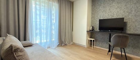Una sala de estar moderna con un sofá, un televisor, una mesa de centro y un taburete pequeño.