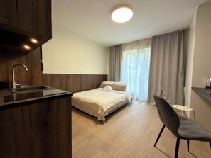 Een moderne hotelkamer met een wand van hout, een bed met witte lakens, een klein bureau met stoel en een raam met gordijnen.