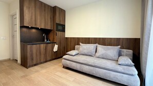 Ein modernes Wohnzimmer mit integrierter Küche, einer Couch und einem Flachbildfernseher.