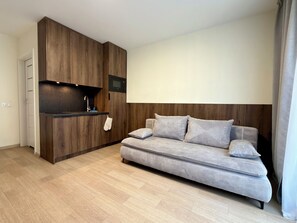 Ein modernes Wohnzimmer mit integrierter Küche, einer Couch und einem Flachbildfernseher.