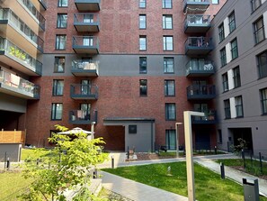 Ein mehrgeschossiges Wohngebäude mit Balkonen, einem kleinen Garten und einem Gehweg.
