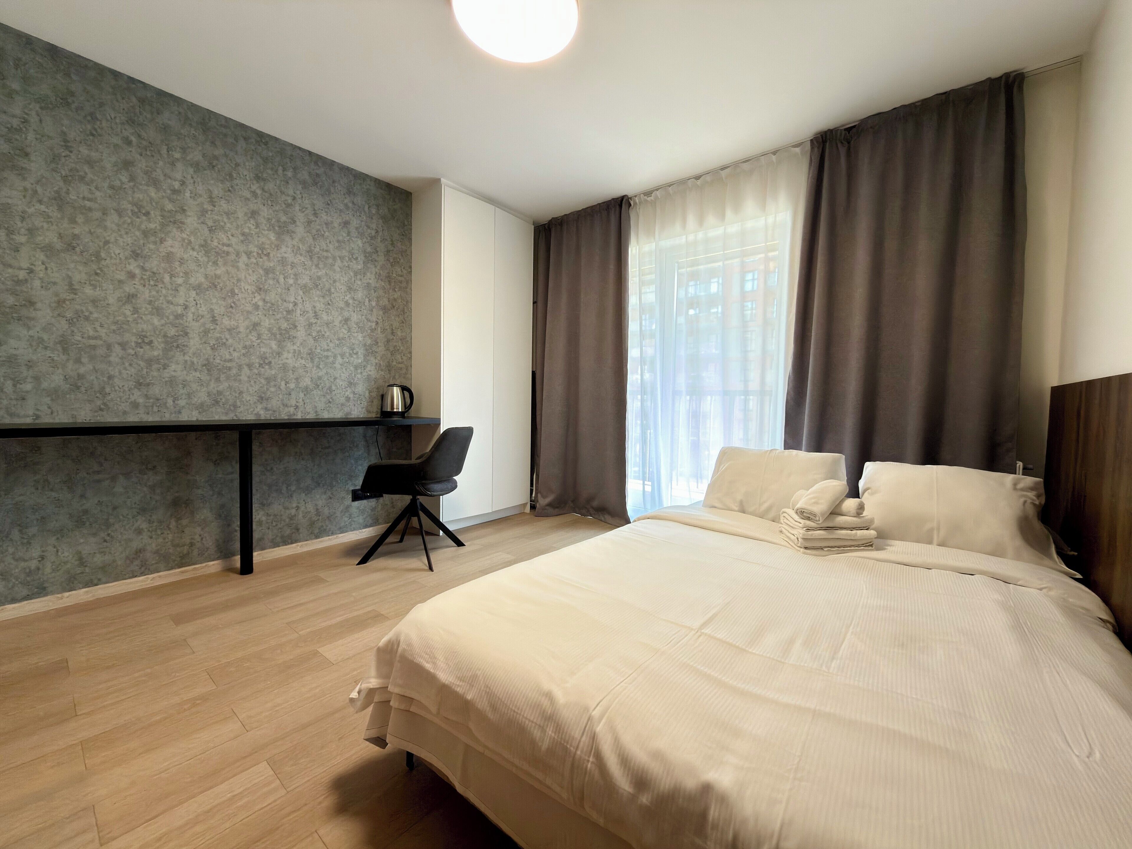 A hotel room with a bed, a desk, and a chair.