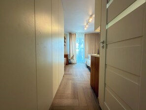 Ein Flur mit einem Bett und einem Schreibtisch am Ende, der zu einem Zimmer mit einem Fenster führt.