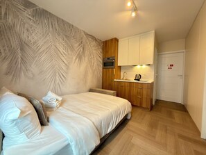 Ein Schlafzimmer mit einem Bett, einer kleinen Küchenzeile und einer Tür.