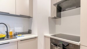 A modern kitchen with a built-in oven, a microwave, and a stainless steel range hood. - Krzywa Harmony Apartment (Katowice)