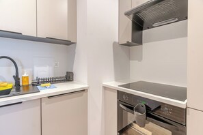 A modern kitchen with a built-in oven, a microwave, and a stainless steel range hood. - Krzywa Harmony Apartment (Katowice)