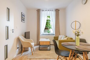 A modern living room with a sofa, chairs, a coffee table, and a dining table. - Krzywa Harmony Apartment (Katowice)