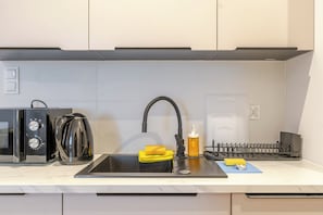 Une cuisine avec un évier noir, une machine à café et un bloc à couteaux.