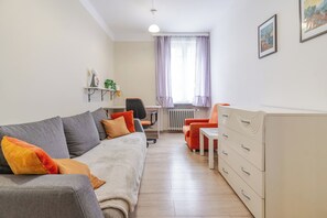 A modern living room with a sofa, a chair, a small table, and a cabinet. - Powstańców Central Apartment (Katowice)