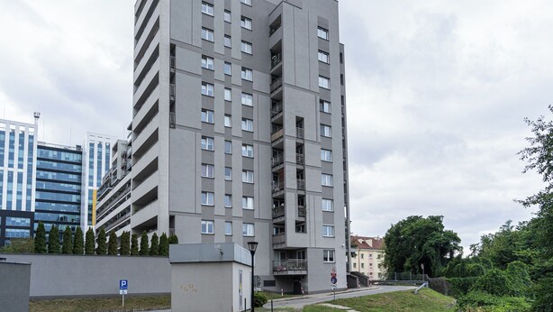Un edificio residencial de varios pisos con balcones, un letrero de estacionamiento y un letrero de prohibido estacionar.