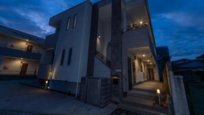 Un bâtiment moderne à deux étages, doté d’un balcon et d’un escalier menant à l’entrée.