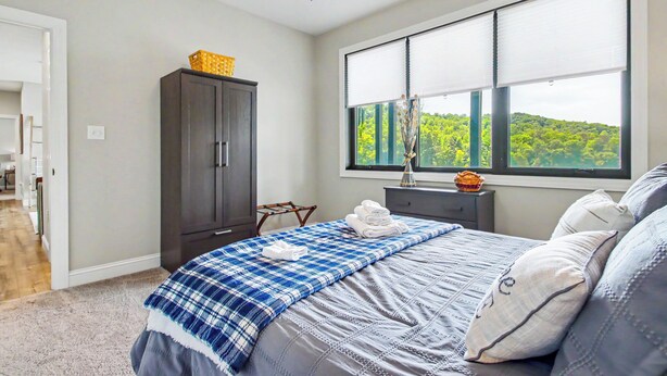 Un dormitorio con cama, armario, ventana con vistas y ventilador de techo.