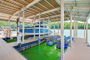 Un quai abrité où est amarré un bateau bleu, avec de l’eau verte et une forêt en arrière-plan.