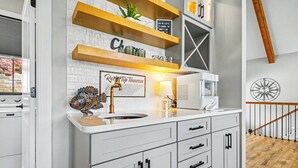 Cocina con armarios blancos, encimera de madera y una escultura decorativa de un pez.