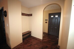 A hallway with a wooden floor, a door, and a bench.