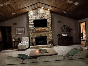 A cozy living room with a stone fireplace, a flat-screen TV, a comfortable sofa, and a coffee table.