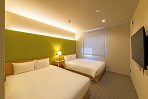 Habitación de hotel con dos camas, una mesita de noche con lámpara, televisor y ventana con persianas.