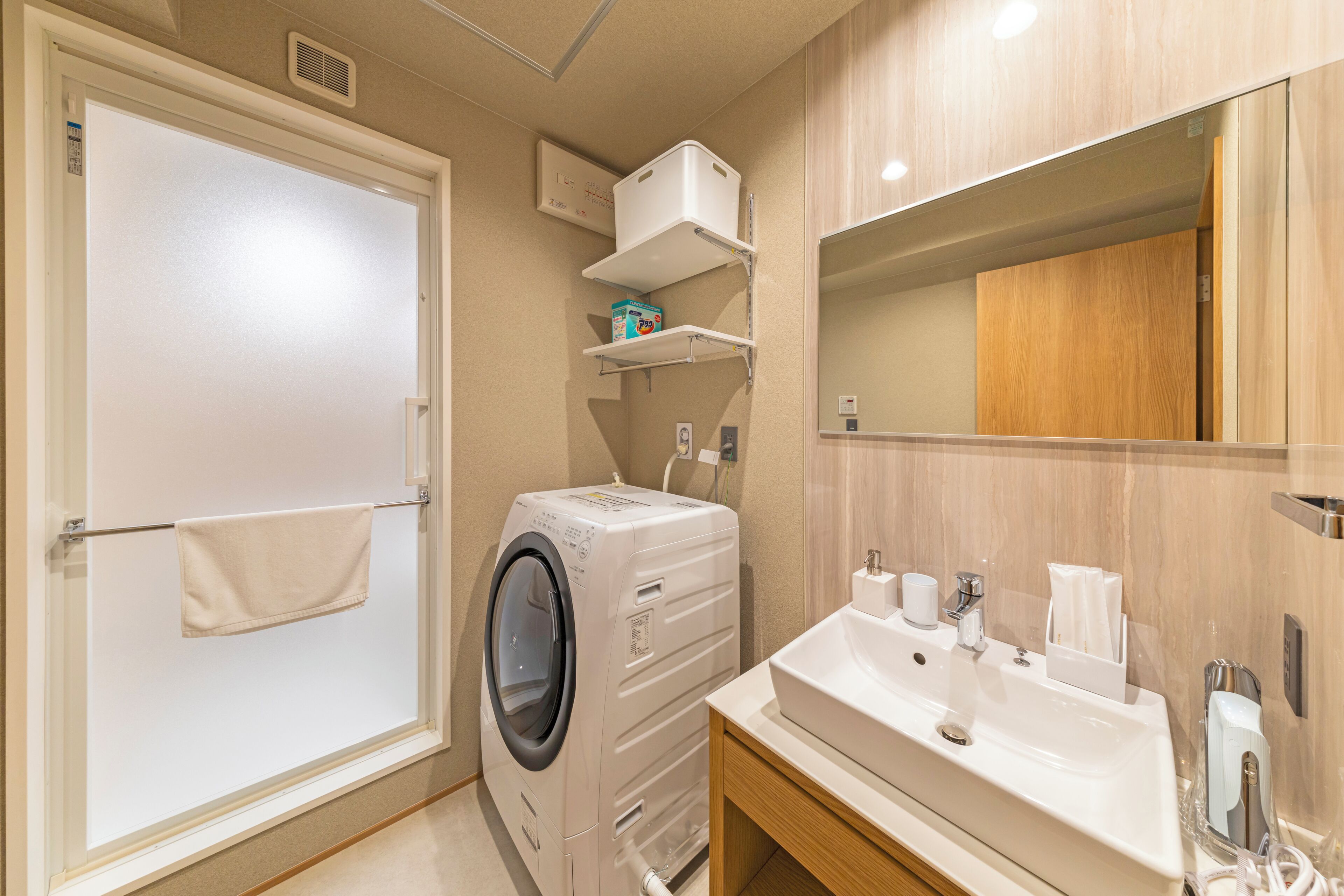Un baño moderno con lavadora y secadora integradas, un lavabo con tocador y un espejo sobre el tocador.