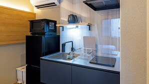 A compact kitchenette with a microwave, a kettle, and a sink with a soap dish.