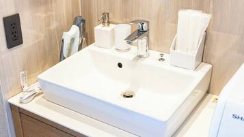 A white bathroom sink with a mirror, a towel dispenser, and a soap dispenser.