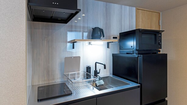 A modern kitchen with a stainless steel sink, a kettle, a microwave, and a built-in oven.