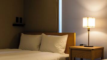 Quarto de hotel com cama, almofadas, mesa de cabeceira e luminária.